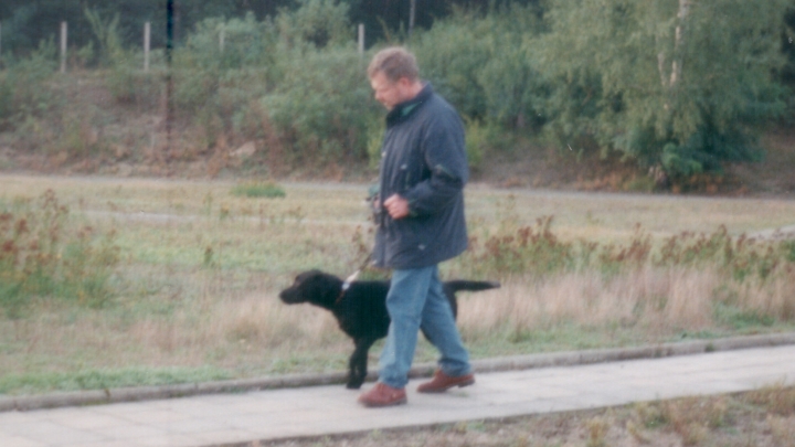 Meine ganze Familie war in die Ausbildung involviert.Mein Vater trainiert auf dem Vereinsgelände. Mann mit schwarzem Labrador übt Fuß.