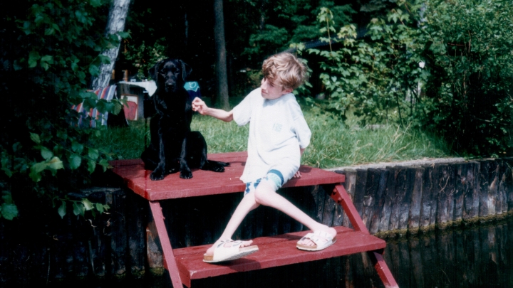 Akiba und ich am See Kind mit schwarzem Labrador sitzen auf einer Treppe am See.